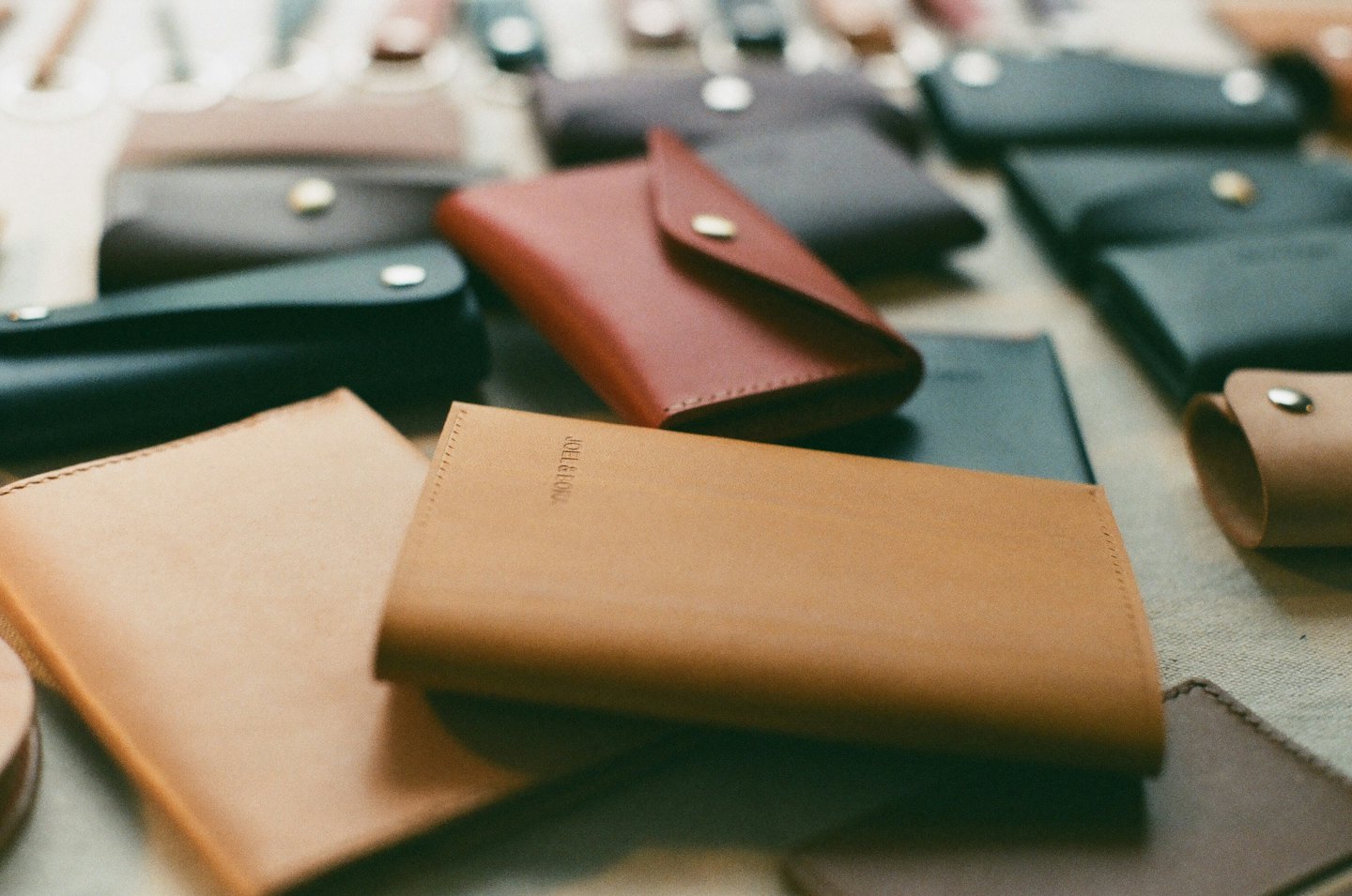 Assorted handcrafted leather wallets and cases on a textured surface.